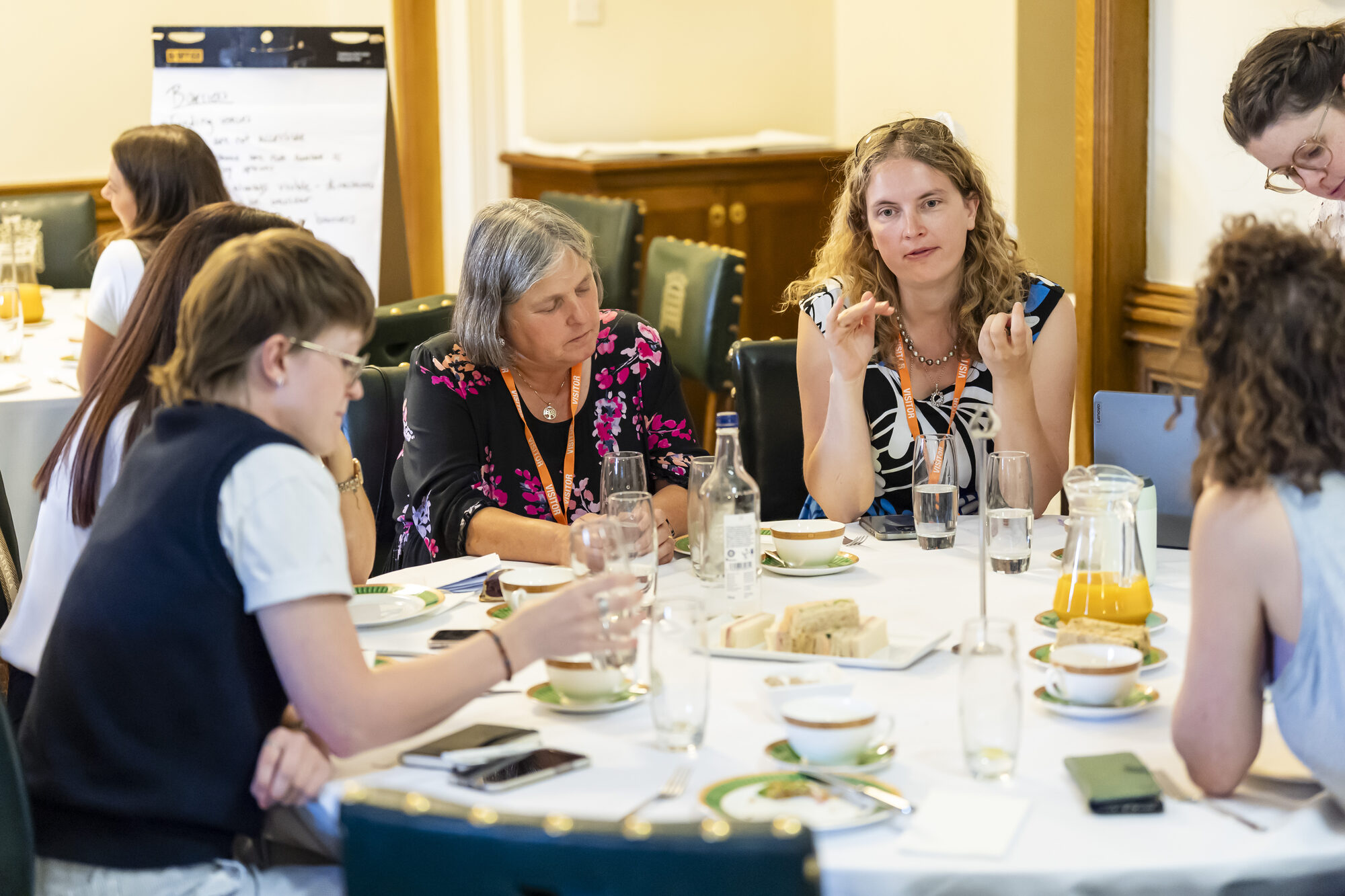 Co-investigator Prof Anica Zeyen is sitting at a round white table with fellow workshop participants. They seem to be involved in a vivid discussion.